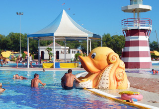 Familier nyder børnevenlig pool med stor blækspruttefigur og fyrtårn på Camping Pra'delle Torri i Veneto.