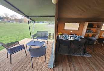 Safari-Zelt mit überdachter Terrasse und Essbereich auf The HappyFarm in den Niederlanden, mit Wiesenblick.