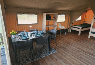Indretning af safari-telt på The HappyFarm, Holland, med spisebord, senge og trægulv.