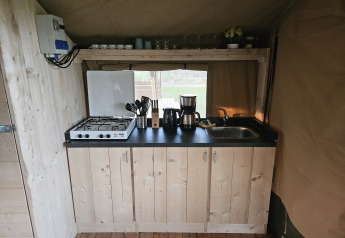 Lille køkken med gaskomfur, håndvask og kaffemaskine i en safariteltsuite på The HappyFarm i Holland.