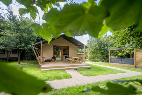 Tenda glamping familiare agli Urban-Gardens Ieper in Belgio, immersa tra alberi e prati verdi.