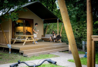 Familia descansando en la terraza de una tienda glamping safari en Urban-Gardens Ieper, Bélgica.