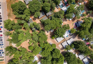 Vista aérea de Camping Park Umag en Istria, Croacia, con árboles, cabañas, casas rodantes y coches aparcados.