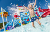Un bambino si diverte e spruzza acqua nel parco acquatico colorato di Camping Park Umag, Istria, Croazia.
