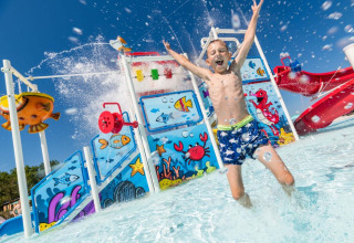 Un bambino si diverte e spruzza acqua nel parco acquatico colorato di Camping Park Umag, Istria, Croazia.