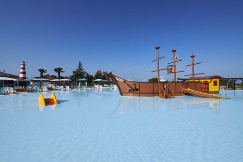 Piscina infantil con barco pirata y tobogán en Camping Park Umag, Istria, Croacia, con cielo despejado.
