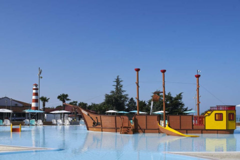 Swimming pool at Camping Park Umag, Croatia, featuring a pirate ship play structure and a lighthouse nearby.