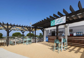 Outdoor Captain Hook Bar seating area at Camping Park Umag, Istria, Croatia, beneath a clear blue sky.