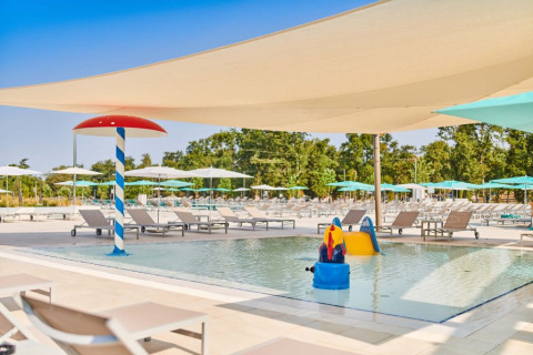 Piscina infantil con tumbonas y juegos acuáticos en Camping Park Umag, Istria, Croacia, bajo velas de sombra.