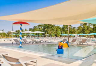 Piscina infantil con tumbonas y juegos acuáticos en Camping Park Umag, Istria, Croacia, bajo velas de sombra.