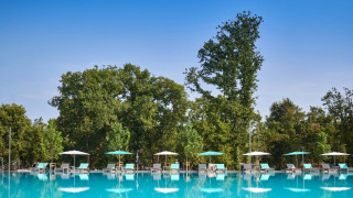 Amplia piscina al aire libre con tumbonas y sombrillas en Camping Park Umag, rodeada de árboles en Istria.