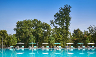 Amplia piscina al aire libre con tumbonas y sombrillas en Camping Park Umag, rodeada de árboles en Istria.