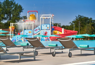 Liegestühle am Pool im Camping Park Umag, mit Wasserrutschen und Spielplatz im Hintergrund, Istrien, Kroatien.