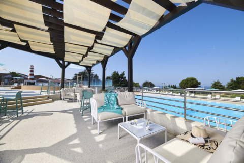 Espace lounge extérieur ombragé avec canapés et vue sur la piscine au Camping Park Umag en Istrie, Croatie.