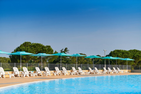 Piscina al aire libre con tumbonas blancas y sombrillas azules en Camping Park Umag, Istria, Croacia.