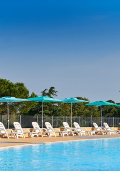 Piscina al aire libre con tumbonas blancas y sombrillas azules en Camping Park Umag, Istria, Croacia.