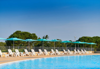 Outdoor swimming pool with white loungers and blue umbrellas at Camping Park Umag, Istria, Croatia.