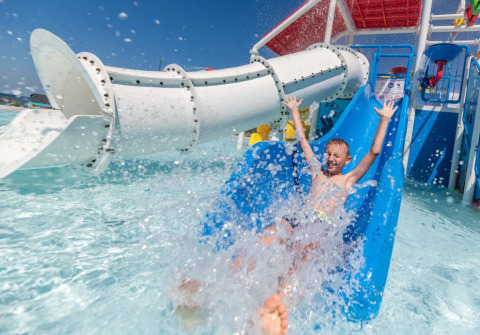 Ragazzo si diverte sullo scivolo blu a Camping Park Umag, parco vacanze in Istria, Croazia, giornata di sole.