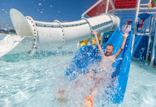 Ragazzo si diverte sullo scivolo blu a Camping Park Umag, parco vacanze in Istria, Croazia, giornata di sole.