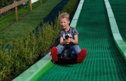 Boy enjoys riding down a green slide at The HappyFarm holiday park in Gelderland, Netherlands.