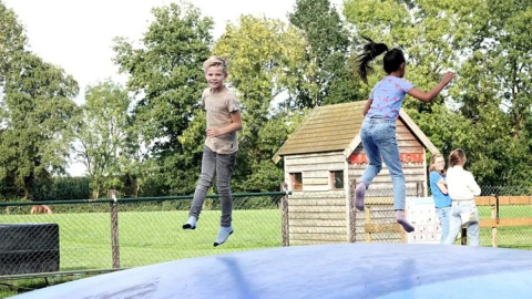 To børn hopper og leger på en stor oppustelig pude på The HappyFarm feriepark i Gelderland, Holland.