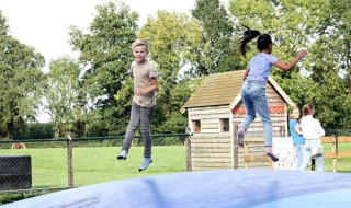 To børn hopper og leger på en stor oppustelig pude på The HappyFarm feriepark i Gelderland, Holland.