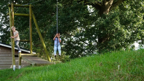 Deux enfants jouent à la tyrolienne en plein air au parc de vacances The HappyFarm à Gelderland, Pays-Bas.