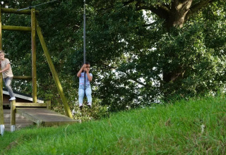 Deux enfants jouent à la tyrolienne en plein air au parc de vacances The HappyFarm à Gelderland, Pays-Bas.