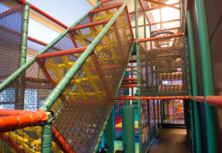 Indoor-Spielplatz mit Klettergerüst und Netzen im HappyFarm Ferienpark, Gelderland, Niederlande.