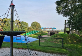 Udendørs legeplads og vandrutsjebaner på The HappyFarm-feriepark i Gelderland, Holland, under en blå himmel.
