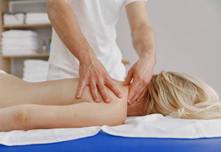 En mand giver en afslappende rygmassage til en kvinde på en massagebriks på Camping Terme Catez, Slovenien.