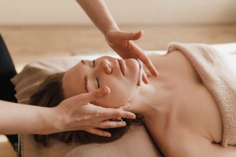 Donna che riceve un massaggio facciale in una spa, avvolta in un asciugamano a Camping Terme Catez, Slovenia.