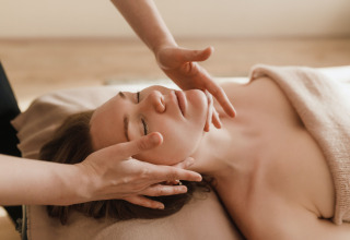 Donna che riceve un massaggio facciale in una spa, avvolta in un asciugamano a Camping Terme Catez, Slovenia.