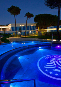 Piscina iluminada y tobogán acuático en Camping Village Cavallino, parque vacacional en Véneto, Italia, de noche.
