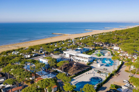 Vista aerea del Camping Village Cavallino in Veneto, Italia, con piscine, bungalow e ampia spiaggia sabbiosa.