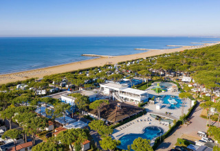 Vista aerea del Camping Village Cavallino in Veneto, Italia, con piscine, bungalow e ampia spiaggia sabbiosa.