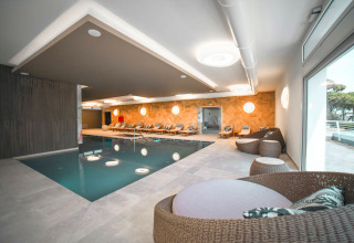 Indendørs pool og afslapningsområde med loungestole på Camping Village Cavallino i Veneto, Italien.