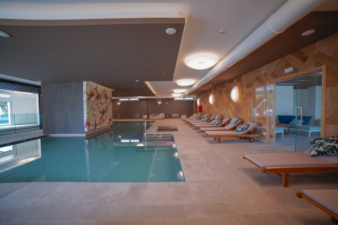 Piscina interna e area relax con lettini al Camping Village Cavallino, villaggio vacanze in Veneto, Italia.