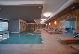 Indendørs pool og afslapningsområde med liggestole på Camping Village Cavallino, feriepark i Veneto, Italien.