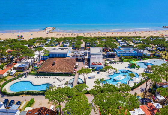 Aerial view of Camping Village Cavallino in Veneto, Italy, showing pools, beach, and holiday lodges.