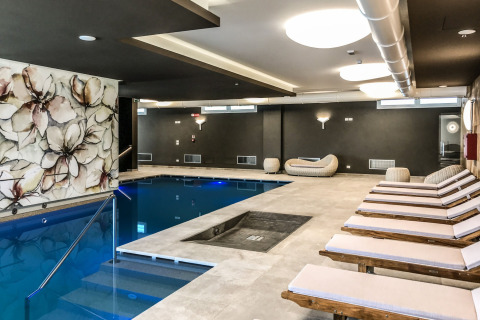 Área de piscina cubierta y tumbonas modernas en Camping Village Cavallino, Veneto, Italia, con elegante decoración.