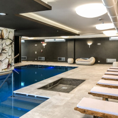 Área de piscina cubierta y tumbonas modernas en Camping Village Cavallino, Veneto, Italia, con elegante decoración.