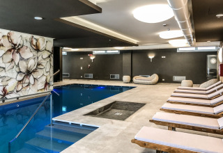 Área de piscina cubierta y tumbonas modernas en Camping Village Cavallino, Veneto, Italia, con elegante decoración.