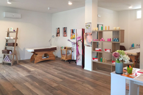 Sala de tratamientos de bienestar con camillas y estantes de productos en Camping Village Cavallino, Italia.