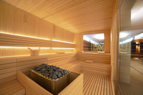 Sauna moderna con bancos de madera y piedras calientes en Camping Village Cavallino, Véneto, Italia.