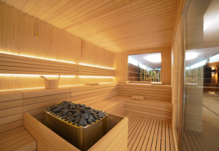 Sauna moderna con panche in legno e pietre calde al Camping Village Cavallino in Veneto, Italia.