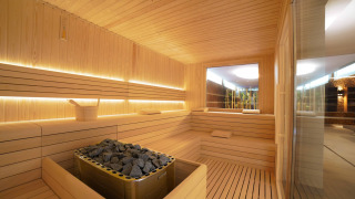 Sauna moderna con bancos de madera y piedras calientes en Camping Village Cavallino, Véneto, Italia.