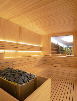 Sauna moderna con bancos de madera y piedras calientes en Camping Village Cavallino, Véneto, Italia.