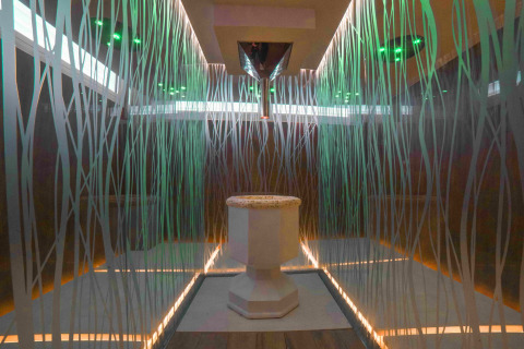 Baño moderno con paredes de cristal, pedestal central y luces de colores en Camping Village Cavallino, Véneto.