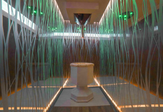 Modern bathroom with glass walls, central pedestal, and colorful lights at Camping Village Cavallino, Veneto.